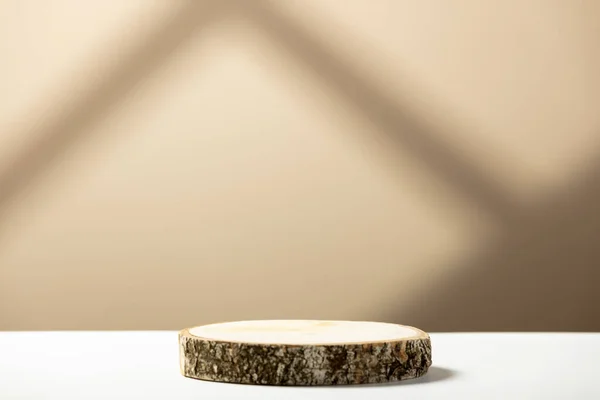 Wood slice podium on a beige background with shadows. Natural cosmetics and beauty concept — 스톡 사진