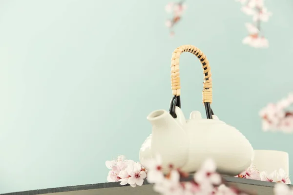 Cute teapot and spring cherry branches on blue background, copy space — Stockfoto