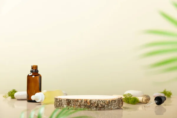 Modna kompozycja butelek z olejkiem eterycznym z bursztynu i pustego okrągłego drewnianego podium do prezentacji produktu na beżowym tle — Zdjęcie stockowe