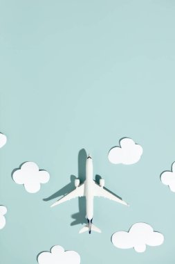 Renkli arka planda minyatür oyuncak uçak ve kağıt bulutlar. Seyahat, tatil, turizm, havayolları, düşük maliyetli uçuş konsepti. Üst manzara, düz uzanma.