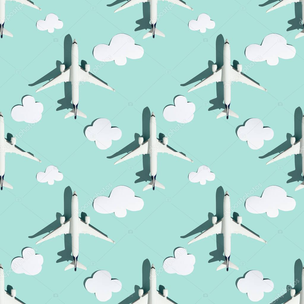Creative composition made with white passenger plane and paper clouds on colorful background. Summer travel or vacation pattern. Flat lay, square composition