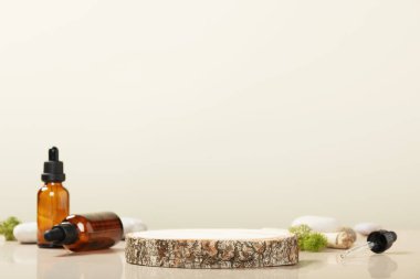 Boş kehribar cam esaslı yağ şişeleri ürün sunumu için boş ahşap podyum yapraklar, yosunlar ve bej arkaplanda taşlar. Organik kozmetik için soyut podyum