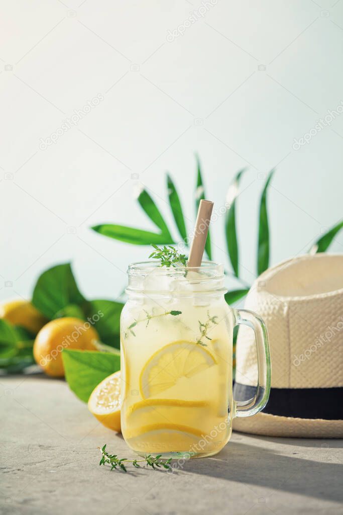Lemonade, summer hat and tropical fruits and leaves close up. Summer cocktails with blue sky on background