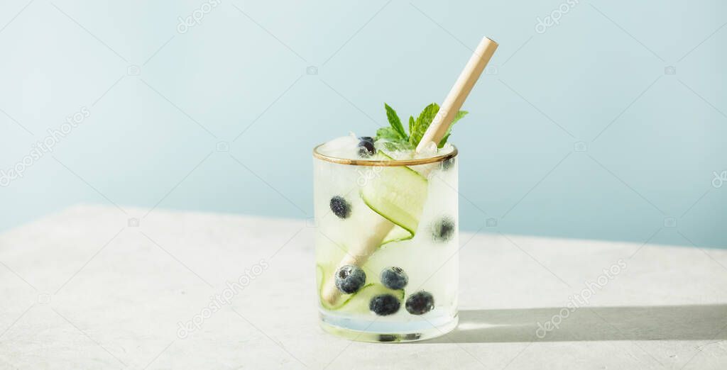 Trendy summer drinks with cucumber, mint and blueberry on blue sky background. Vacation concept