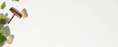 Tirbuşonlu şarap kompozisyonu, şarap şişesi mantarı, üzüm ve güzel güneş ışığı ve beyaz arka planda gölgeler. Üst manzara, düz uzanma