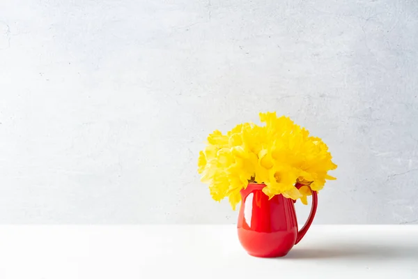 桌上红色水壶中的一束黄色水仙花 室内装饰 复制空间 — 图库照片
