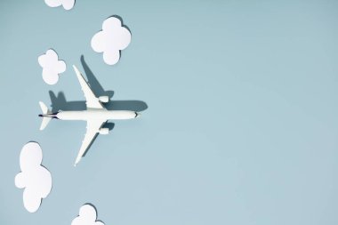 Renkli arka planda minyatür oyuncak uçak ve kağıt bulutlar. Seyahat, tatil, turizm, havayolları, düşük maliyetli uçuş konsepti. Üst manzara, düz uzanma.