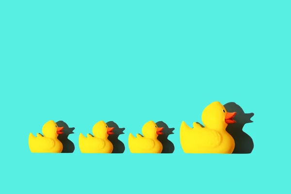 Rubber toy of yellow color Mama-duck and small ducklings on a blue background. The concept of maternal care and love for children, the upbringing and education of children