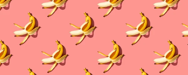 Yellow ripe bananas on pink background pattern, banner. Minimal style. Flat lay.