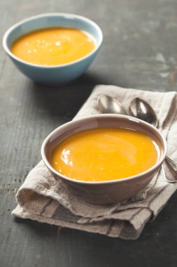 Pumpkin soup in a bowls on a wooden surface close up