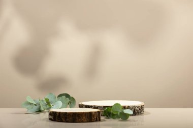 Tarafsız bej arka planda minimal modern ürün görüntüsü. Tahta kürsü ve yeşil yapraklar. Yeni ürün için konsept sahne gösterisi, tanıtım satışı, afiş, sunum, kozmetik