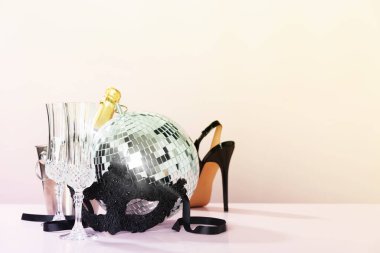 Party time concept. Christmas, New years eve, Carnival, masquerade. Mask, champagne, party shoes and disco ball, copy space