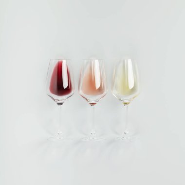 Flat-lay of red, rose and white wine in glasses on white background. Wine bar, winery, wine degustation concept. Minimalistic trendy photography. Square composition