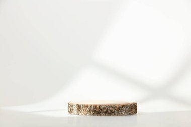 Beyaz arka planda minimal modern ürün görüntüsü. Tahta kesimi podyum ve geometrik gölgeler. Yeni ürün için konsept sahne gösterisi, tanıtım satışı, afiş, sunum, kozmetik