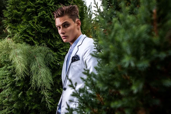 Portrait of young beautiful fashionable man against autumn garden. — Stock Photo, Image