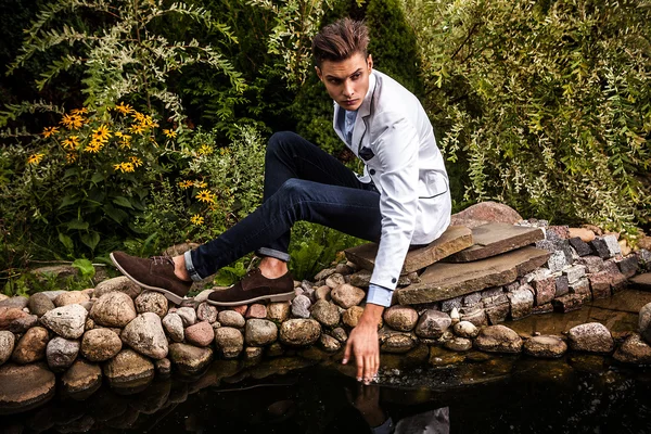 Portrait of young beautiful fashionable man against autumn garden. — Stock Photo, Image