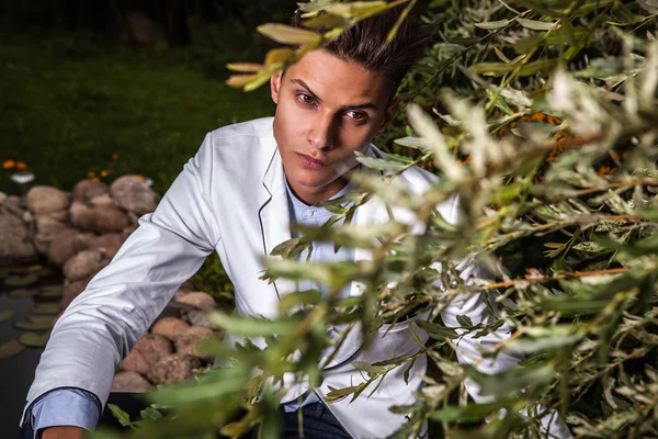 Portret van jonge mooie modieuze man tegen herfst tuin. — Stockfoto