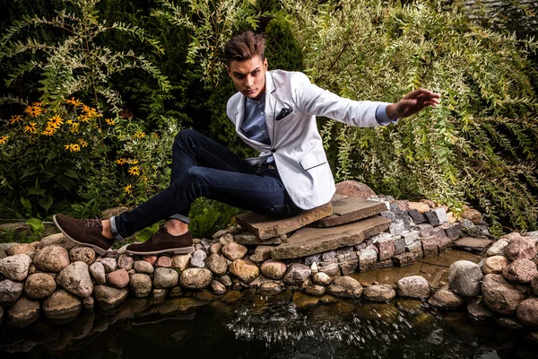 Retrato de joven hermoso hombre de moda contra el jardín de otoño . — Foto de Stock