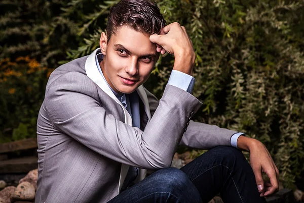 Retrato de joven hermoso hombre de moda contra el jardín de otoño . — Foto de Stock