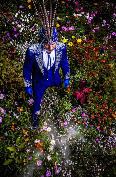 Hombre en traje azul oscuro caro de pose ilusionista en prado de flores . — Foto de Stock