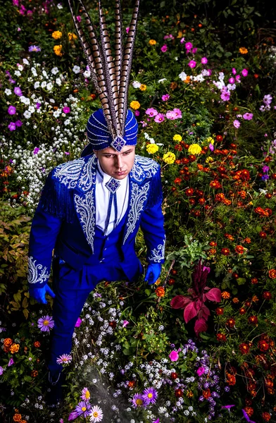 Homem em terno azul escuro caro de pose ilusionista no prado da flor . — Fotografia de Stock