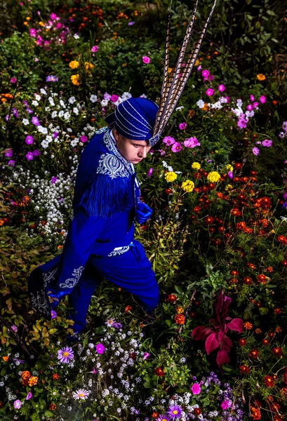 Man in expensive dark blue suit of illusionist pose on flower meadow. — Stock Photo, Image