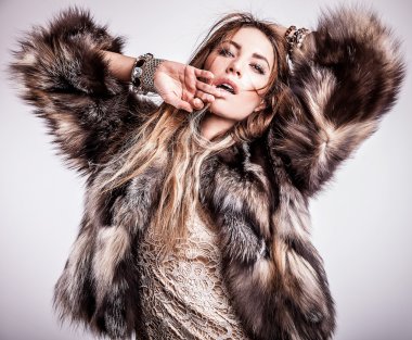 Portrait of attractive stylish woman in fur against grey background.
