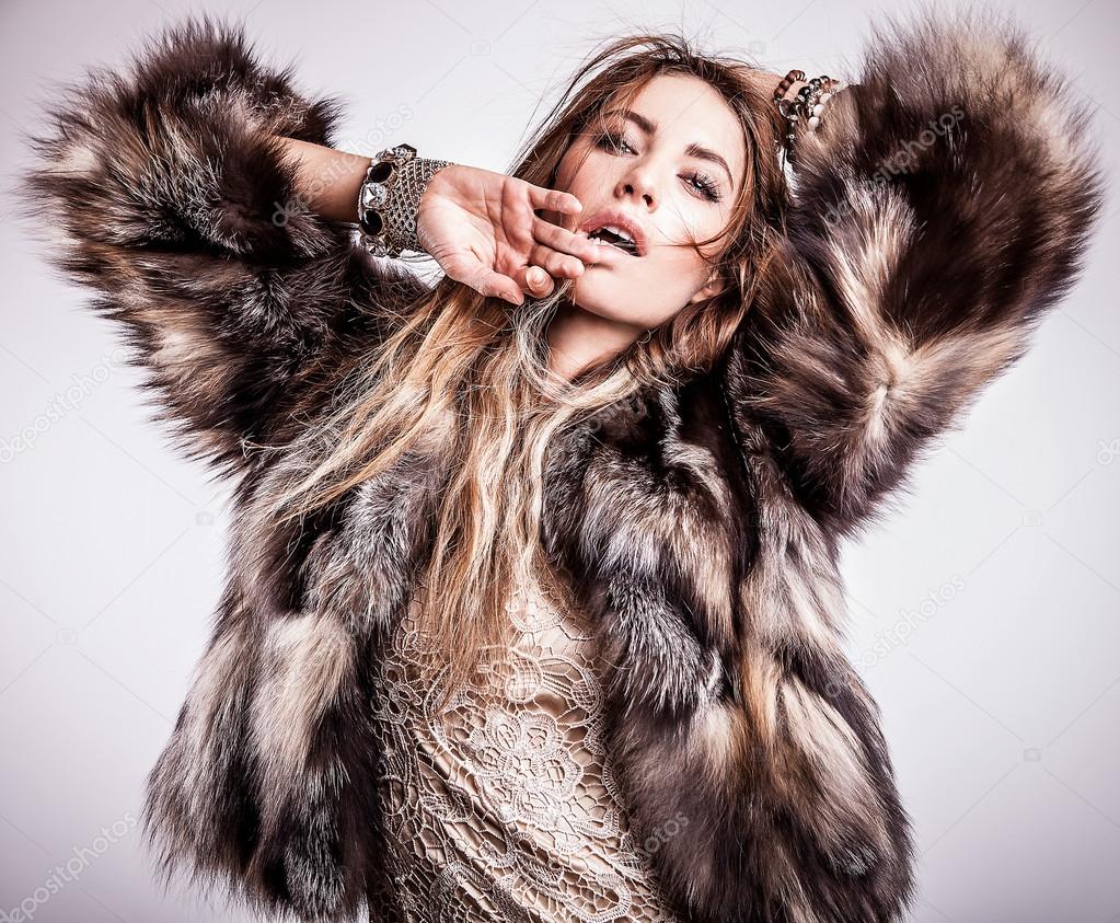 Portrait of attractive stylish woman in fur against grey background.