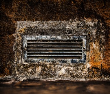 taş duvara gömülü eski paslı kirli havalandırma ızgara.