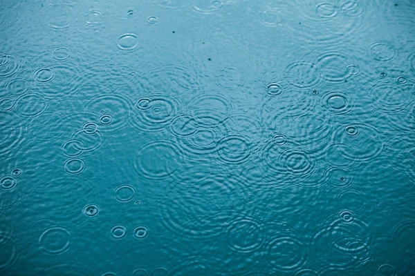 Rain drops falling on clear water. Background photo. — Stock Photo, Image