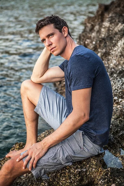 Relaxed attractive man sit at evening near water.