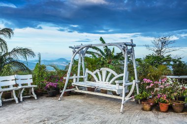Çiçeklerin yanında muhteşem ahşap salıncak.