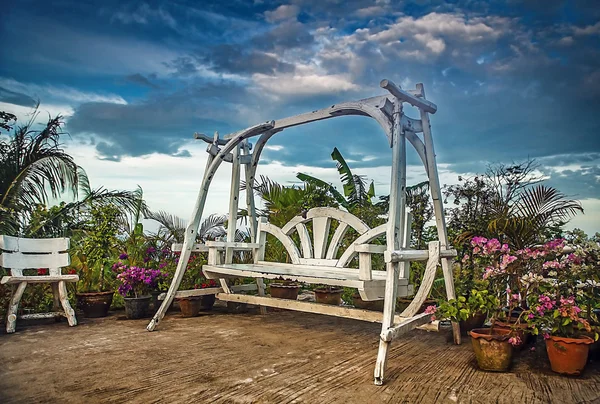 Splendid wooden swing next to the flowers. — Stock Photo, Image