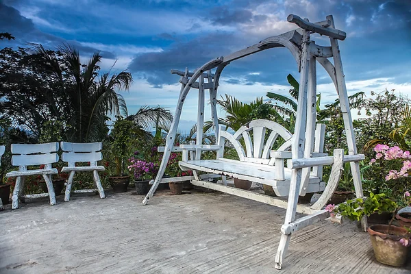 Splendid wooden swing next to the flowers. — Stock Photo, Image