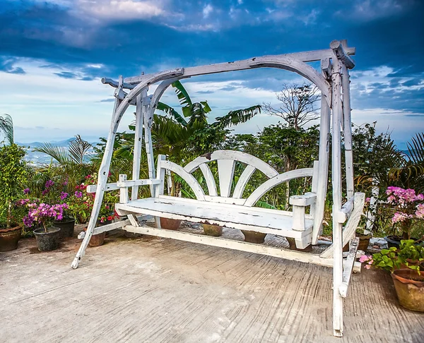 Splendid wooden swing next to the flowers. — Stock Photo, Image