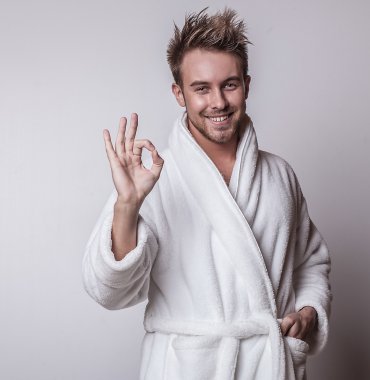 Handsome smiling young man in luxurious bathrobe. clipart