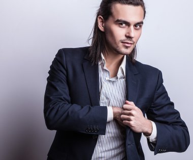zarif genç yakışıklı uzun saçlı adam kostüm. Studio moda portre.