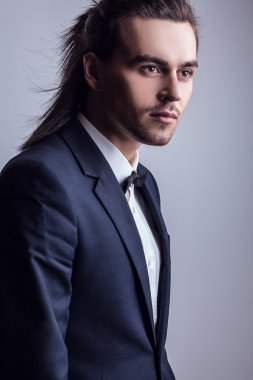 zarif genç yakışıklı uzun saçlı adam kostüm. Studio moda portre.