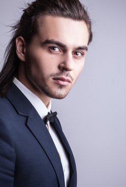zarif genç yakışıklı uzun saçlı adam kostüm. Studio moda portre.