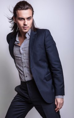 zarif genç yakışıklı uzun saçlı adam kostüm. Studio moda portre.