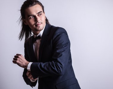 zarif genç yakışıklı uzun saçlı adam kostüm. Studio moda portre.