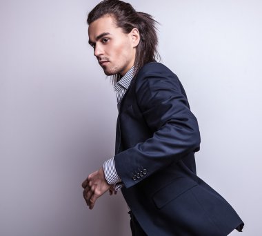 zarif genç yakışıklı uzun saçlı adam kostüm. Studio moda portre.