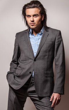 zarif genç yakışıklı uzun saçlı adam kostüm. Studio moda portre.