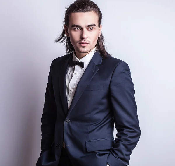 Elegante jonge knappe langharige man in kostuum. Studio mode portret. — Stockfoto