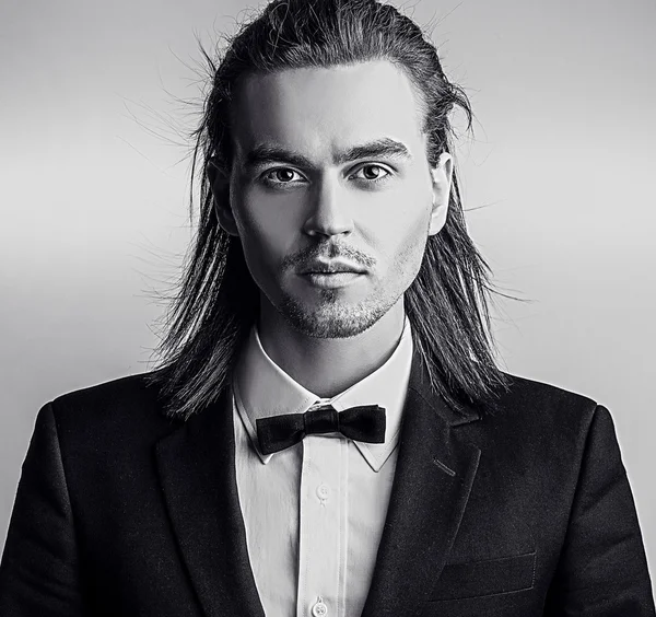 Elegant young handsome long-haired man in costume. Studio fashion portrait. — Stock Photo, Image