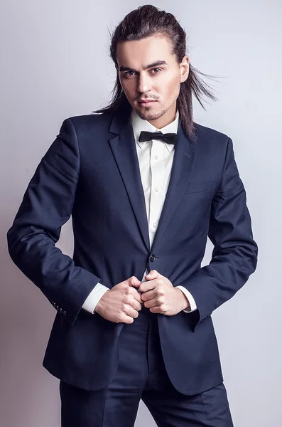 Elegante giovane uomo dai capelli lunghi in costume. Studio ritratto di moda . — Foto Stock