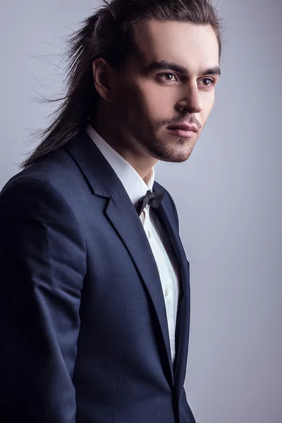 Zarif genç yakışıklı uzun saçlı adam kostüm. Studio moda portre. — Stok fotoğraf