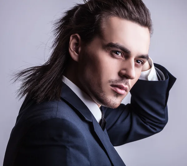 Elégant jeune homme aux cheveux longs en costume. Studio portrait de mode . — Photo