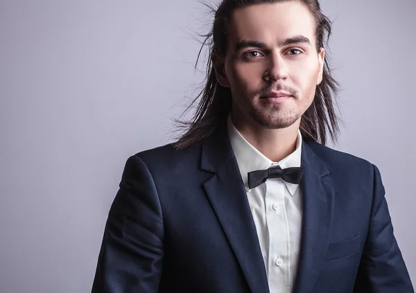 Elegante giovane uomo dai capelli lunghi in costume. Studio ritratto di moda . — Foto Stock