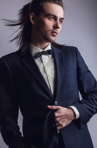 Elegante jonge knappe langharige man in kostuum. Studio mode portret. — Stockfoto